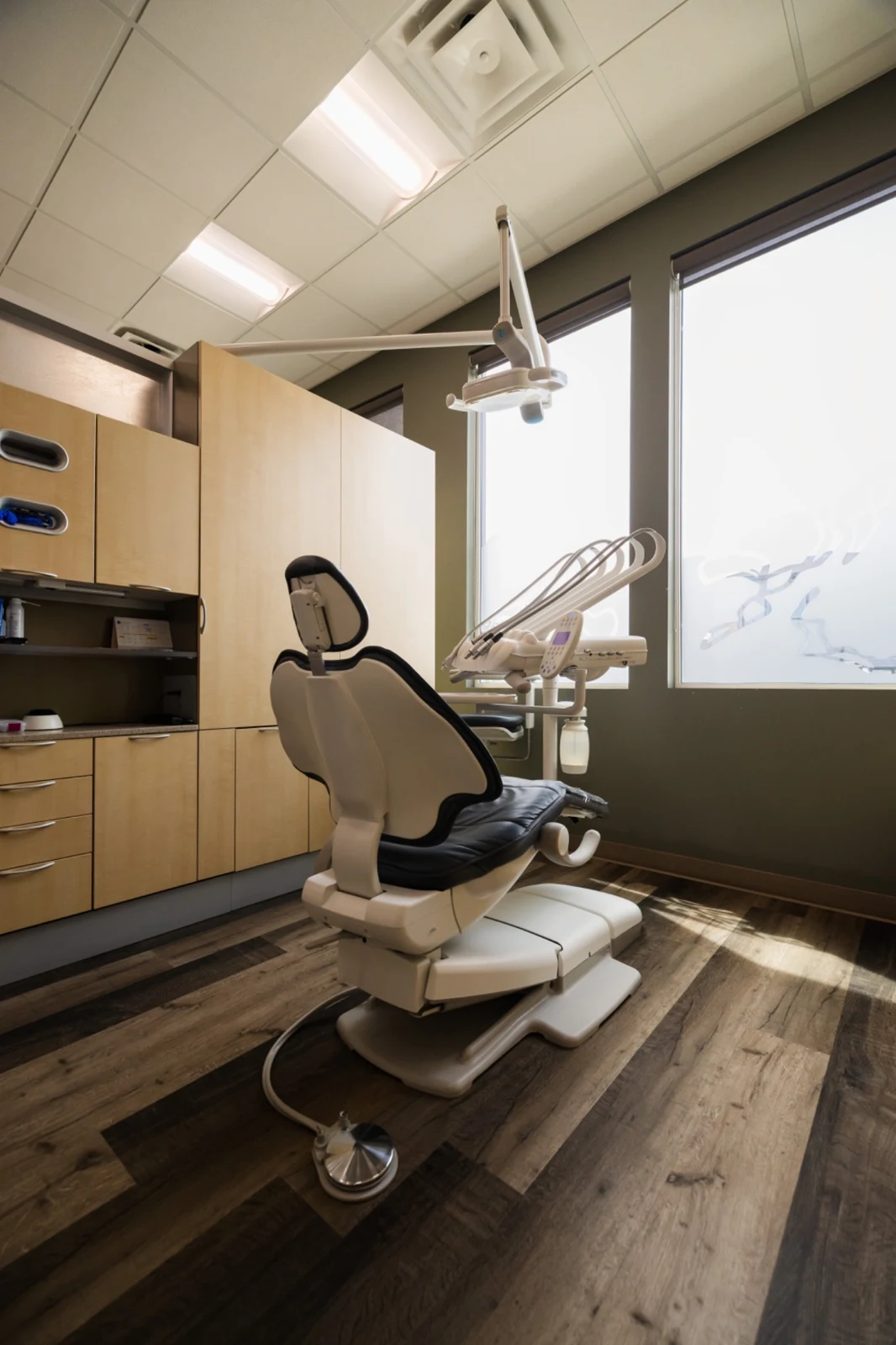 A bright treatment room with a dental chair beside a large window